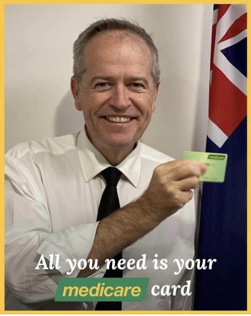 Bill Shorten smiling and holding up a Medicare card.